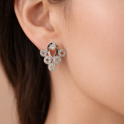 Close-up of a silver AD Earrings for Women with clear stones on an ear against a neutral background