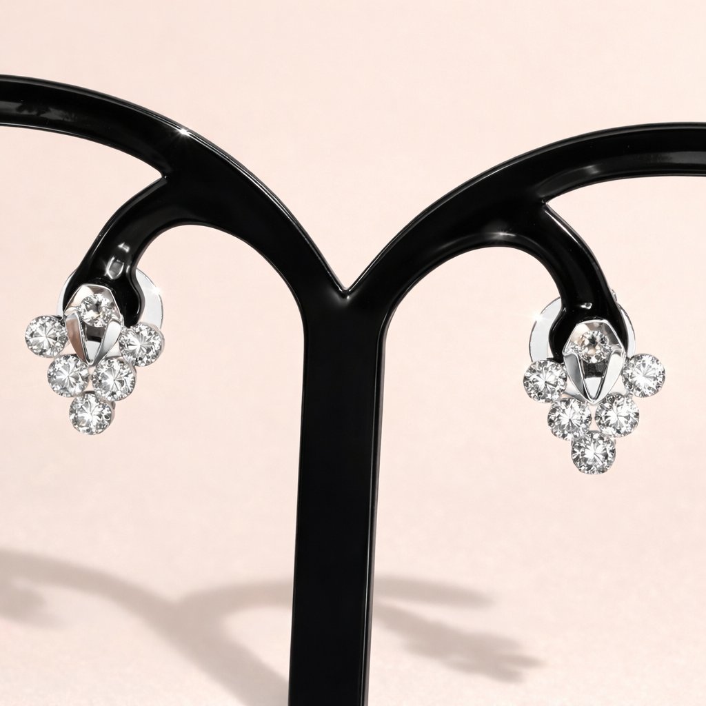 Pair of silver AD Earrings for Women on a black stand against a light pink background