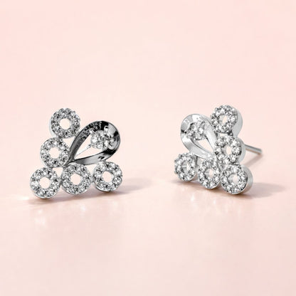 Butterfly-shaped silver AD Earrings for Women with clear gemstones on a pink background