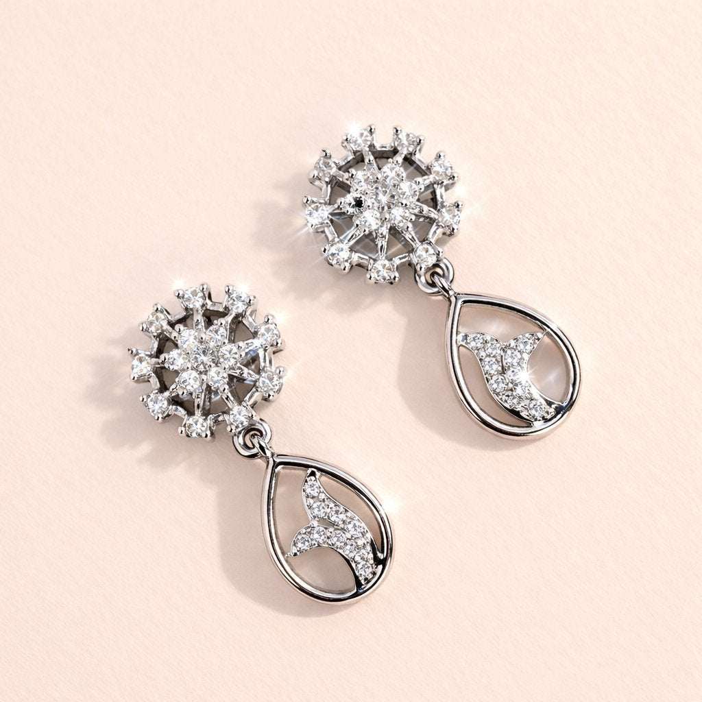 Pair of silver AD Earrings for Women with floral and moon designs on a light pink background