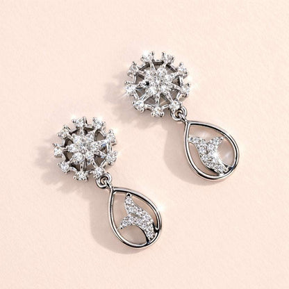 Pair of silver AD Earrings for Women with floral and moon designs on a light pink background