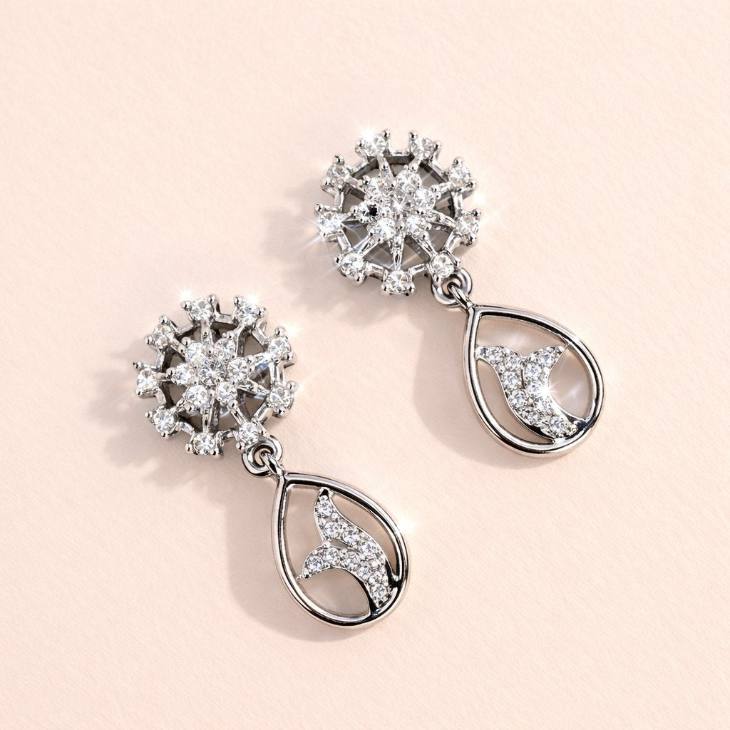 Pair of silver AD Earrings for Women with floral and moon designs on a light pink background