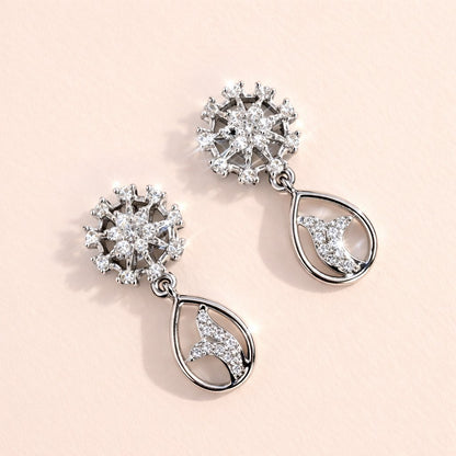 Pair of silver AD Earrings for Women with floral and moon designs on a light pink background