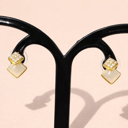 Gold and beige AD Earrings for Women on a black stand with a light pink background