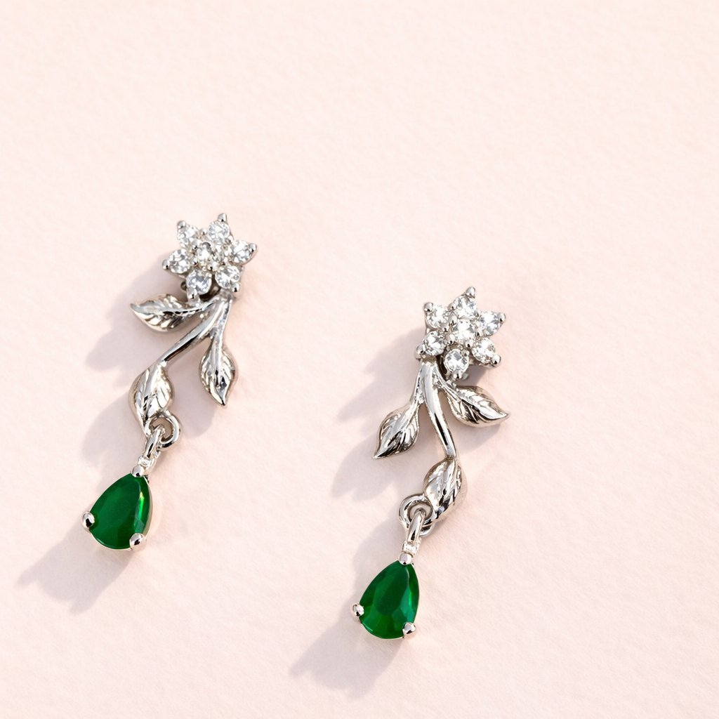 Silver AD Earrings for Women with green gemstones on a light pink background