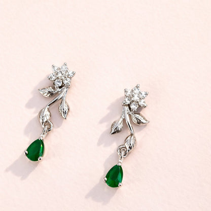 Silver AD Earrings for Women with green gemstones on a light pink background