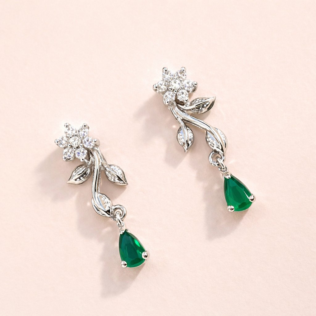 Pair of AD Earrings for Women with emerald drops on a light pink background