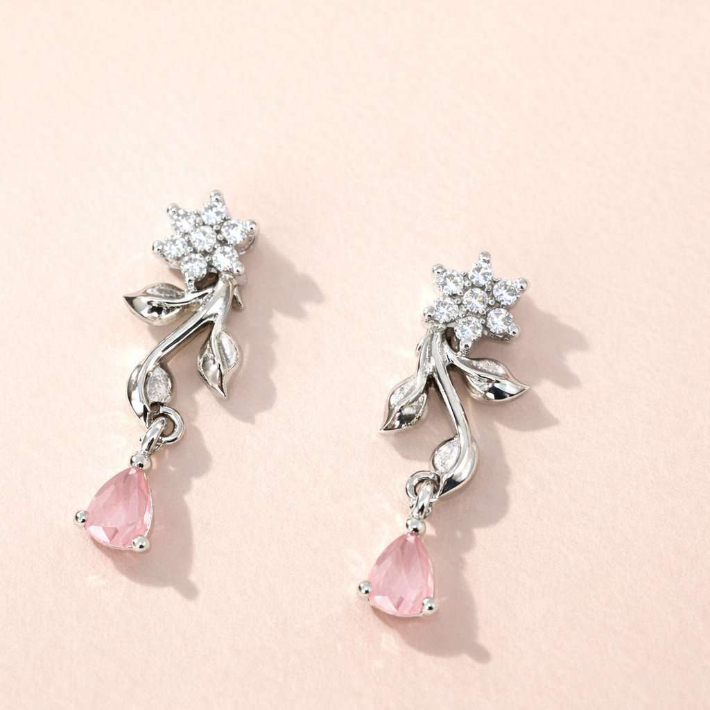 Pair of AD Earrings for Women with pink teardrop stones and silver floral designs on a light pink background