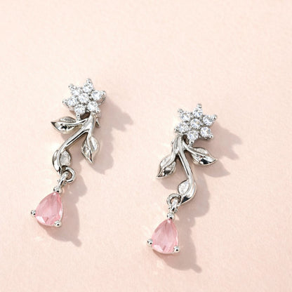 Pair of AD Earrings for Women with pink teardrop stones and silver floral designs on a light pink background