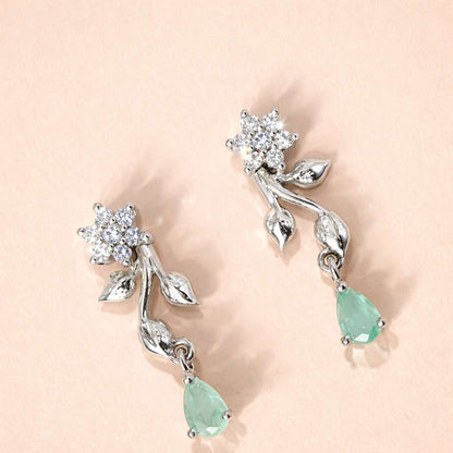 Silver AD Earrings for Women with green gemstones on a light pink background
