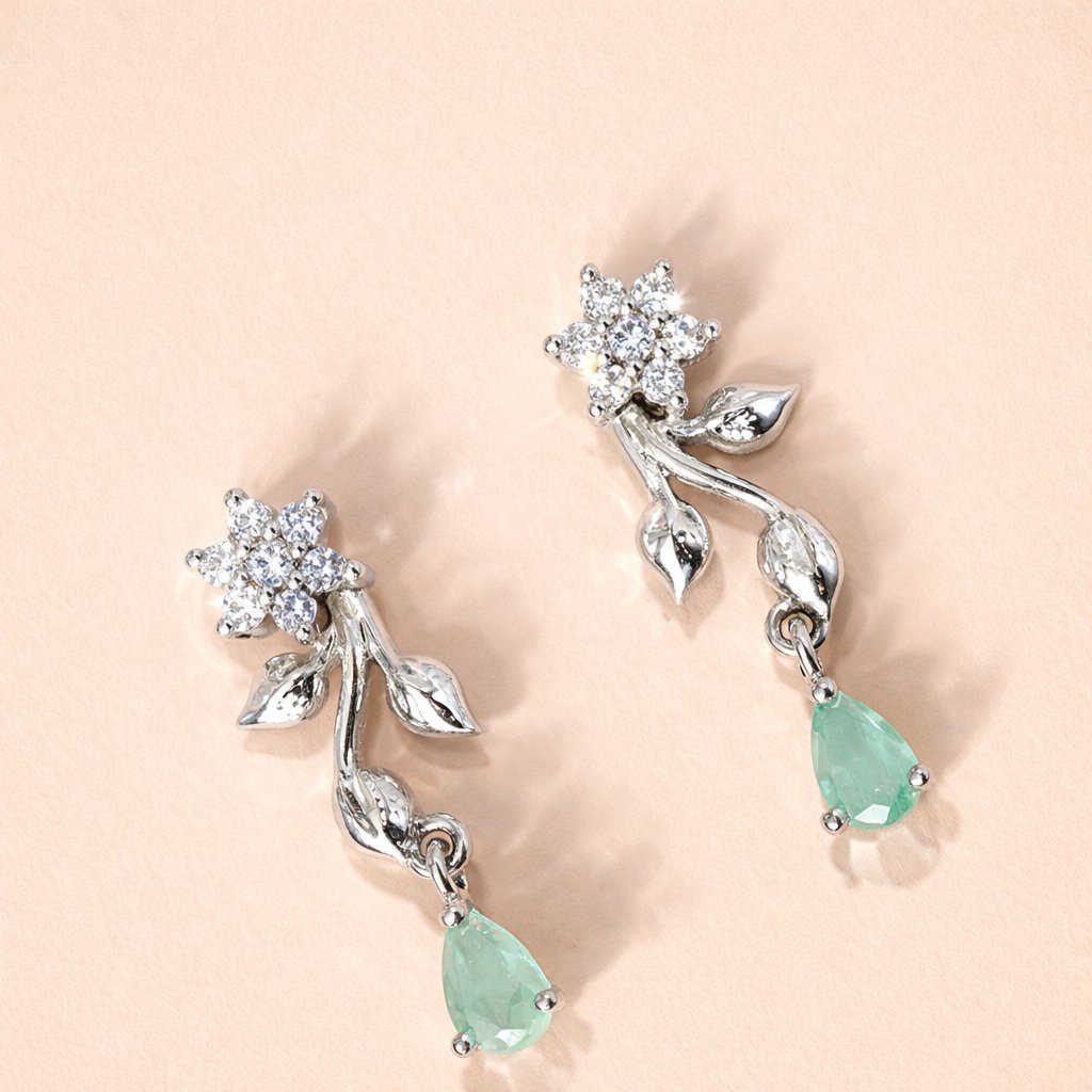 Silver AD Earrings for Women with green gemstones on a light pink background