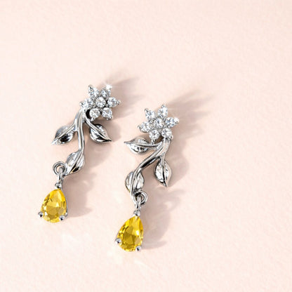 Silver AD Earrings for Women with yellow gemstones on a light pink background