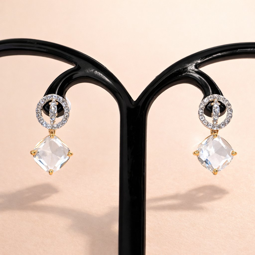 Pair of AD Earrings for Women with clear gemstones on a black stand against a beige background