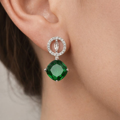 Close-up of a green gemstone AD Earrings for Women on an ear with a neutral background