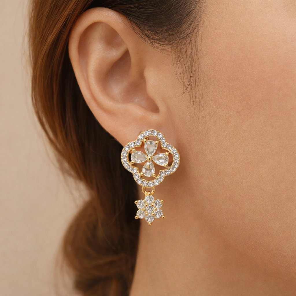 Close-up of a woman's ear wearing a gold and diamond earring against a beige background