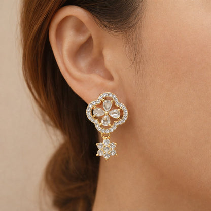 Close-up of a woman's ear wearing a gold and diamond earring against a beige background
