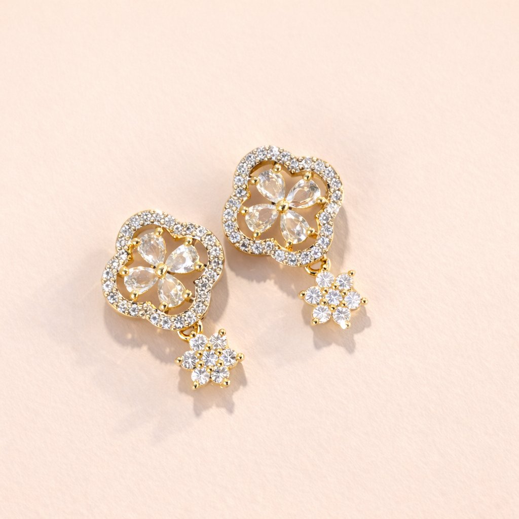 Gold Earrings for Women with clear gemstones on a light pink background
