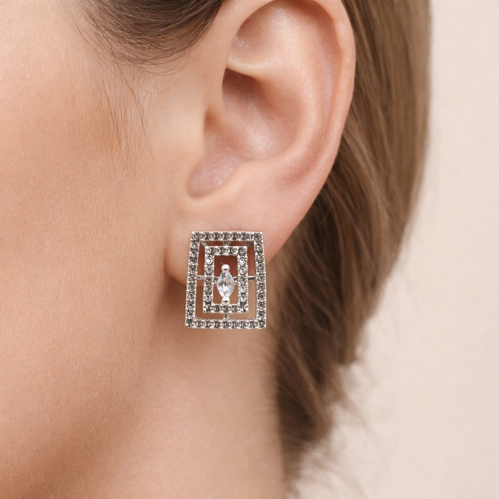 Close-up of a woman's ear wearing a square, multi-layered diamond earring. The earring has a central marquise diamond, exuding elegance and sophistication.