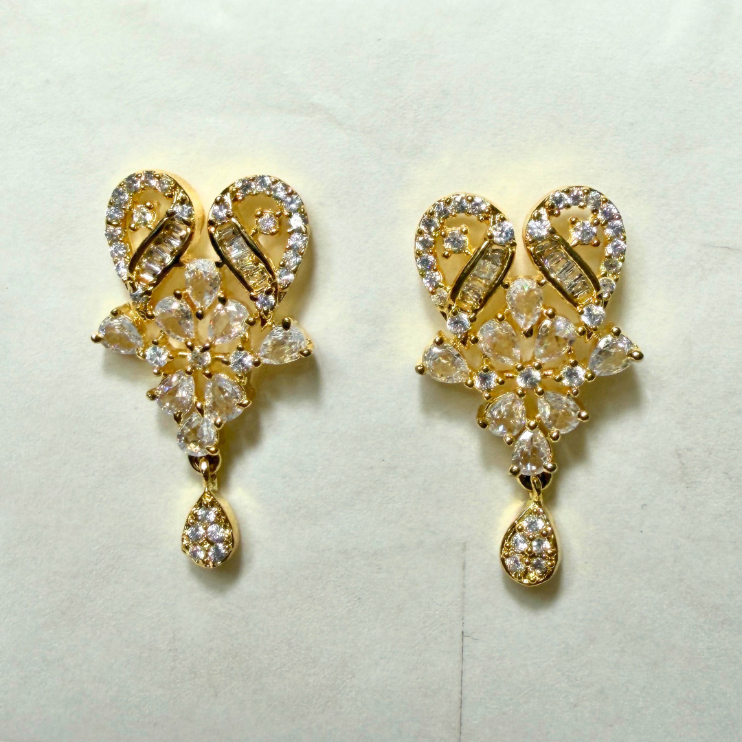 Gold AD earrings with clear gemstones on a light background