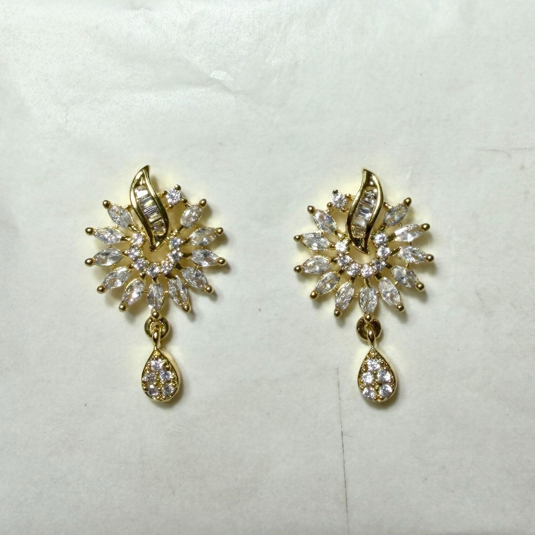 Gold earrings with clear gemstones on a white background