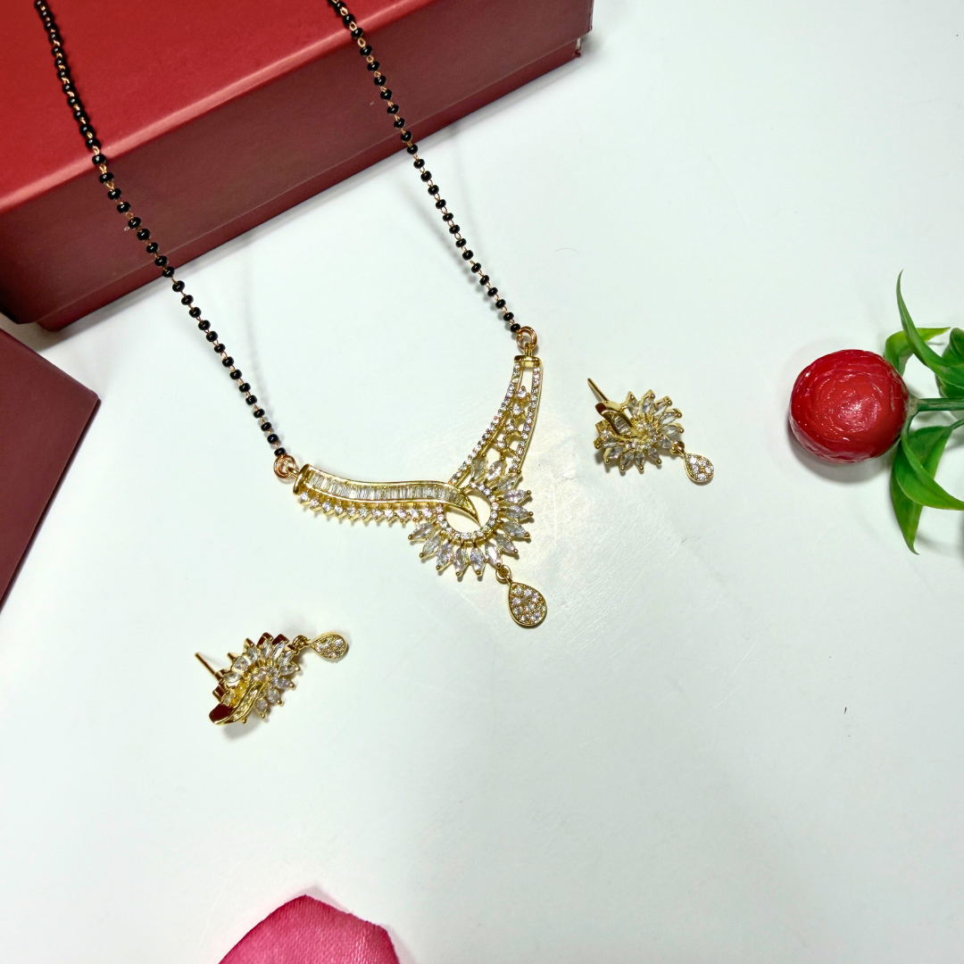 Gold AD Mangalsutra and earrings on a white surface with a red box and decorative elements.