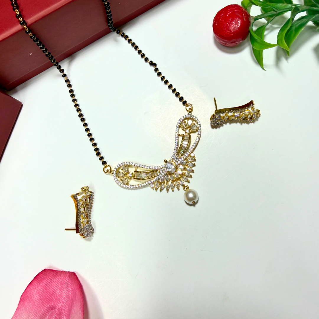 Gold AD Mangalsutra with black beads and earrings on a white surface with decorative elements.