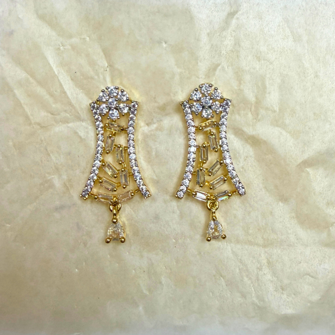 Gold earrings with gemstones on a beige textured background