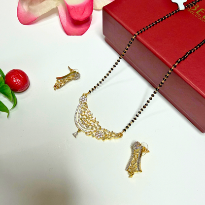 Gold necklace with pendant on a white surface with a red box in the background