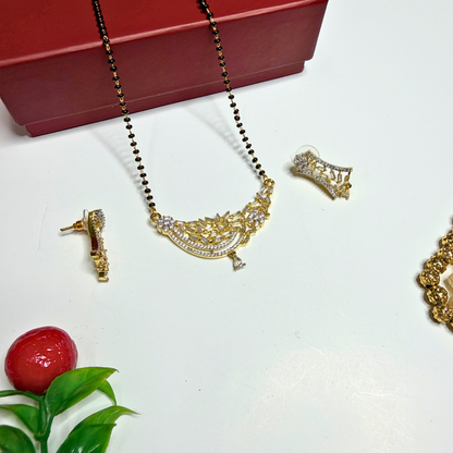 Gold necklace and earrings with a red box on a white surface.