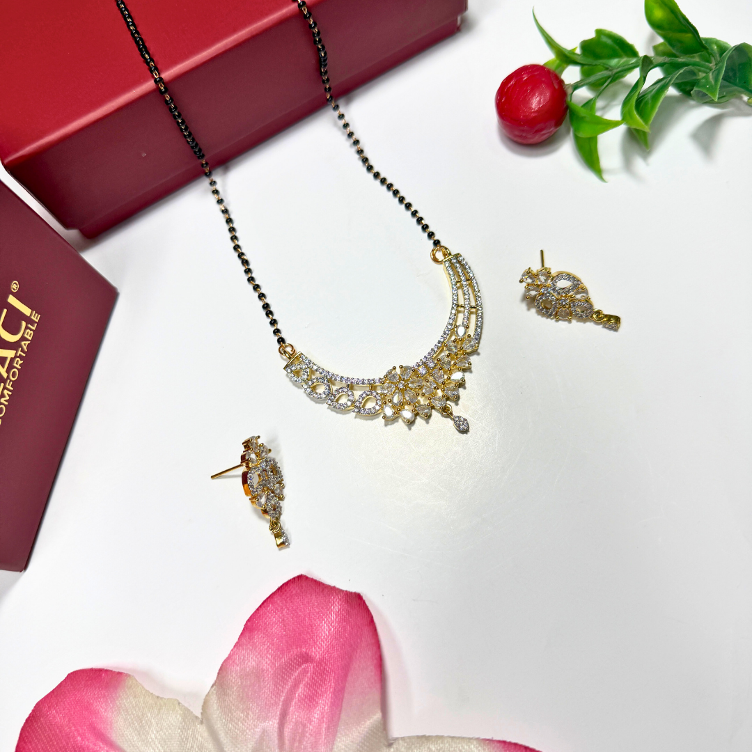 Gold AD Mangalsutra and earrings on a white surface with a red box and pink flower petals.