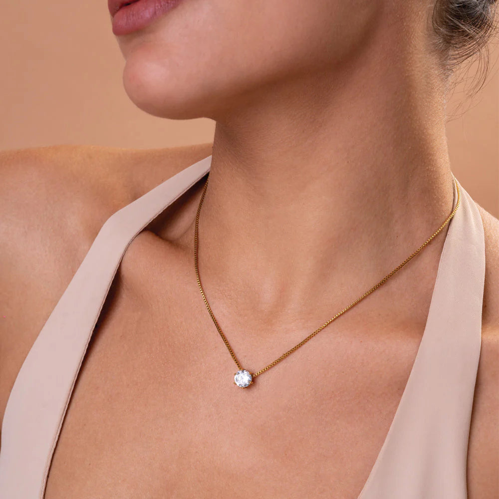 Necklace with a diamond pendant worn by a person against a neutral background