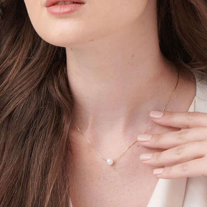 Woman wearing a delicate gold necklace with a small pearl Pendant for Women.