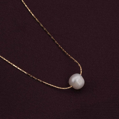 Gold Pendant for Women with a single pearl on a dark fabric background