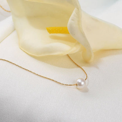 Pearl Pendant for Women on a white surface with a soft yellow fabric background