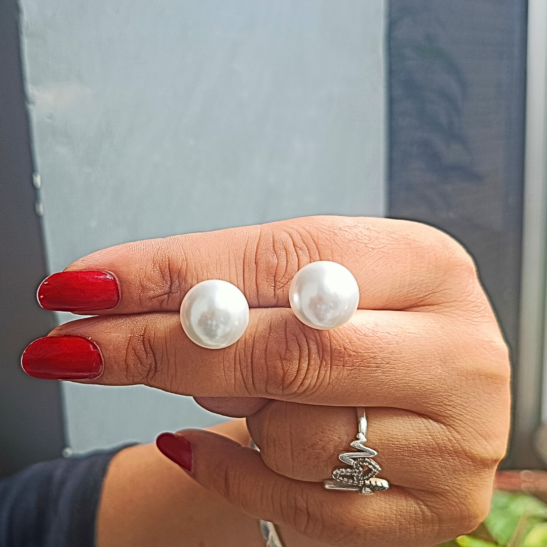 Hand wearing pearl Earrings for Women with a blurred background