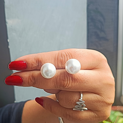 Hand wearing pearl Earrings for Women with a blurred background