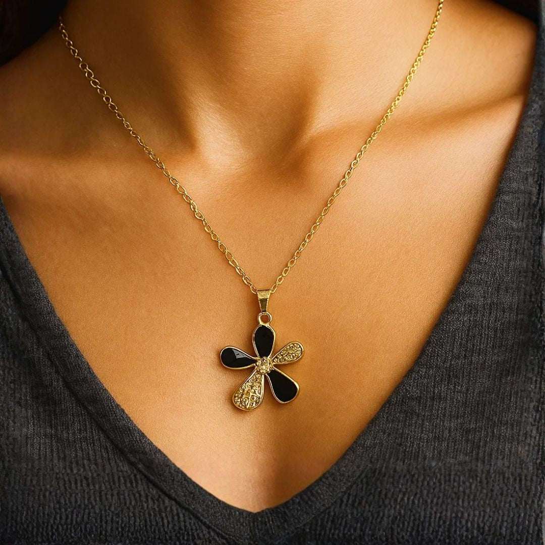Gold necklace with a black and gold pendant worn by a person
