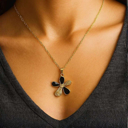 Gold necklace with a black and gold pendant worn by a person