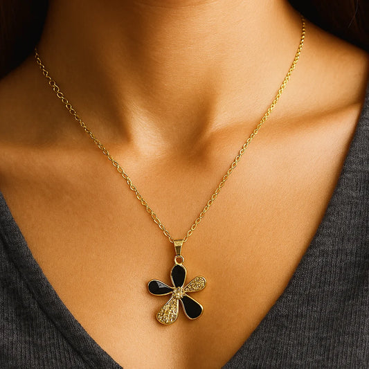 Gold necklace with a black and gold pendant on a person wearing a dark top.